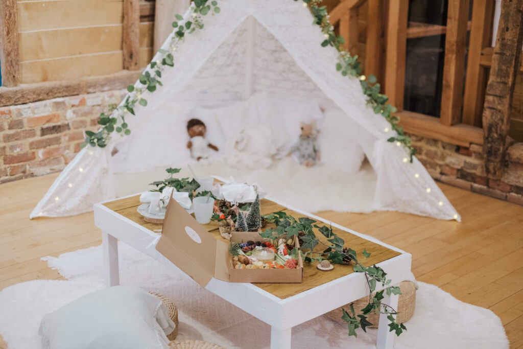 Greenery-styled teepee with a kids' activity table at a wedding venue