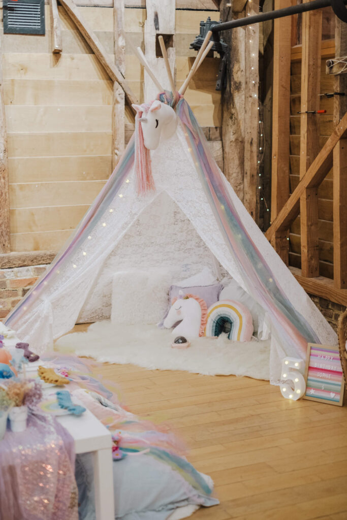 Dressed sleepover teepee with patterned cushions in a barn setting